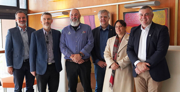 A group of executives pose for a photo in a room adorned with Indigenous artwork