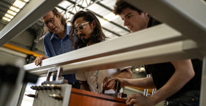 allegro Three men examine flow battery technology in a production facility