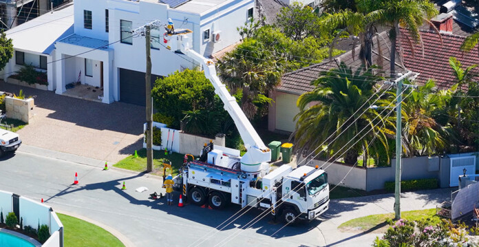 Utility worker in a crane bucket works on power line in residential street