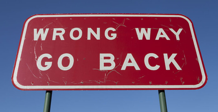 wrong-way-sign Large red road sign saying WRONG WAY GO BACK with blue sky overhead