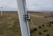 Aussie firm buys robotic bug that inspects turbine blades BladeBug robot deployed on a wind turbine blade with wind farm in the background