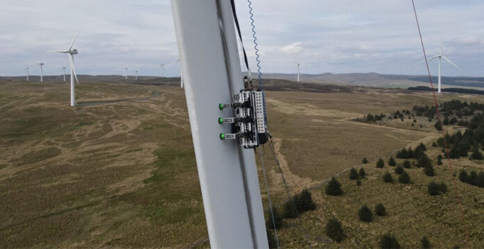 BladeBug robot deployed on a wind turbine blade with wind farm in the background