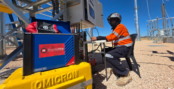 Male worker in high-vis workwear sits near Brandis Hire-branded equipment on a job site