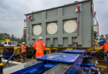 Giant shunt reactors arrive for HumeLink transmission project Giant shunt reactor with work crew in high-vis gear surrounding it