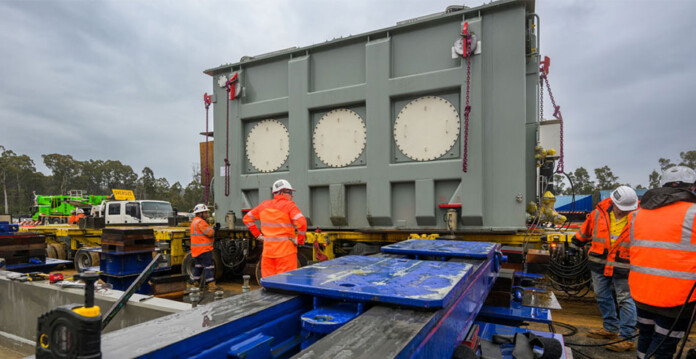 Giant shunt reactor with work crew in high-vis gear surrounding it