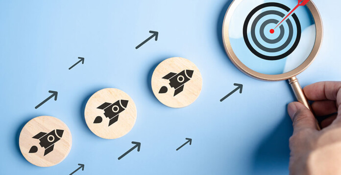 small wooden discs with rocket motifs are positioned heading towards a magnifying glass with a target icon inside it