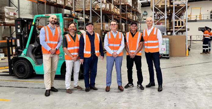 Group of male executives from MGAC and Zenith Energy pose for photo in warehouse