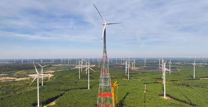 Aerial shot of a wind farm with conventional wind turbines and a massive 365m-tall wind turbine in the centre