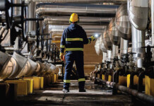 New guide on thermal energy storage for industry Worker in safety gear stands in centre of room with industrial heat plant