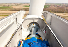 New wind turbine generator test and repair facility for WA Wind turbine with cover off exposing motor, with wind farm in background