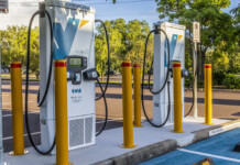 Ampol inks deal to acquire Evie EV charging network Two public Evie Networks EV charging bays with urban street and trees in background